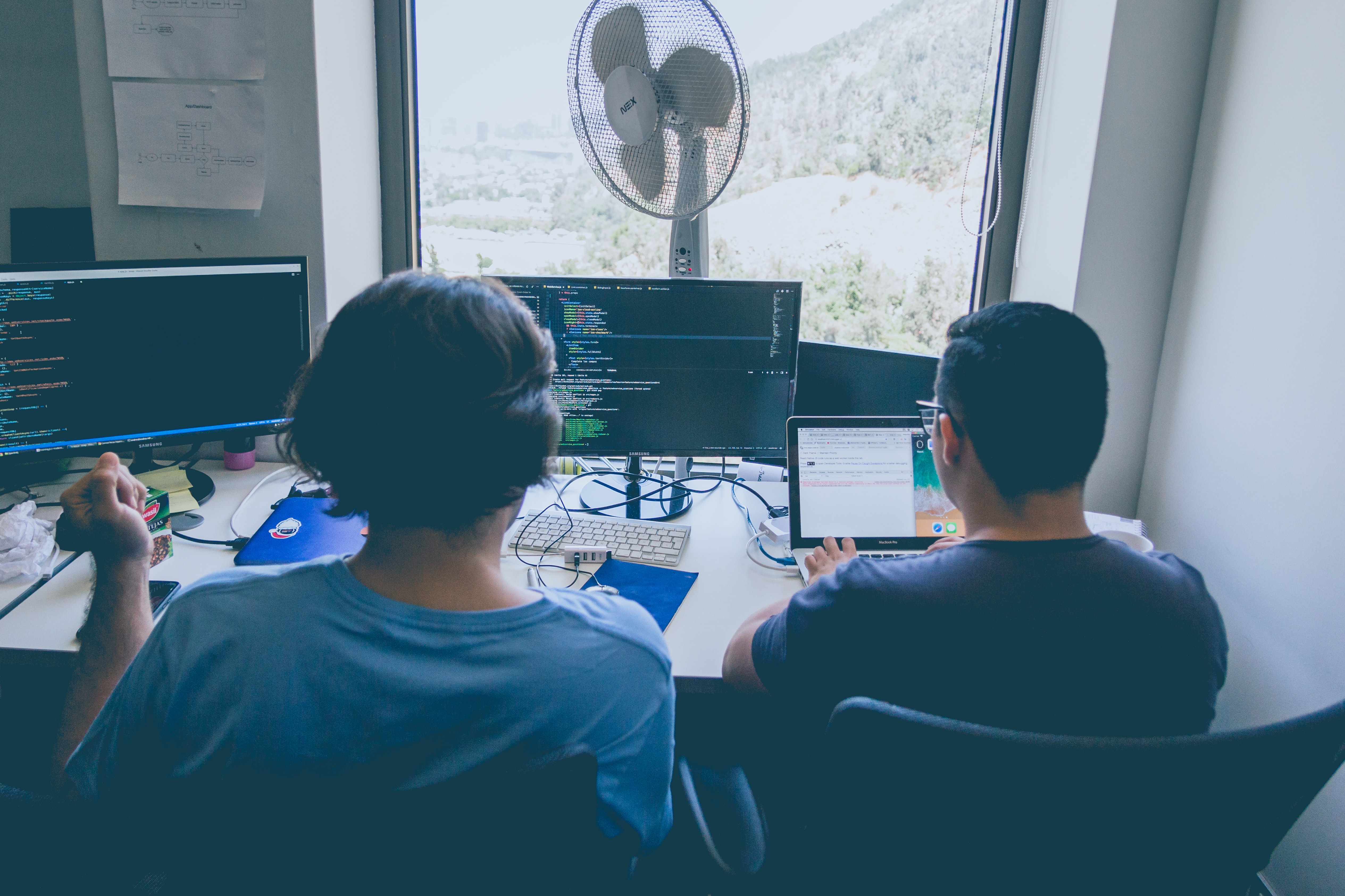 Two persons sitting in front of a computer cooperating on a problem